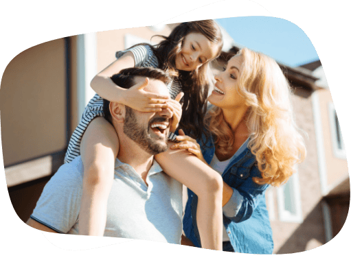 Casal com uma filha, que está sentada nos ombros do pai tapando seus olhos