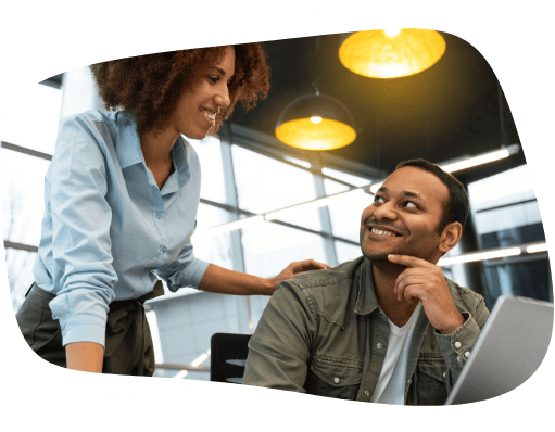 Homem e mulher se olham em frente a um notebook